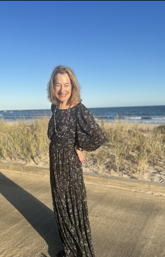Debbie Sullivan standing on a beach boardwalk in a long floral dress