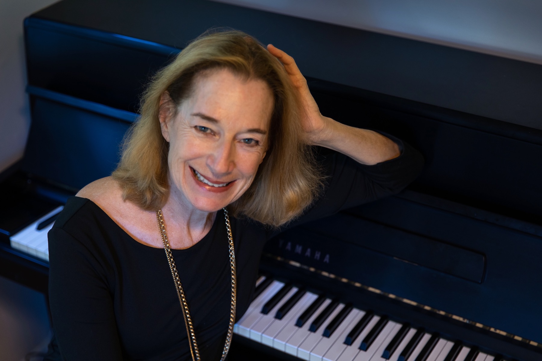 Debbie Sullivan smiling beside a piano