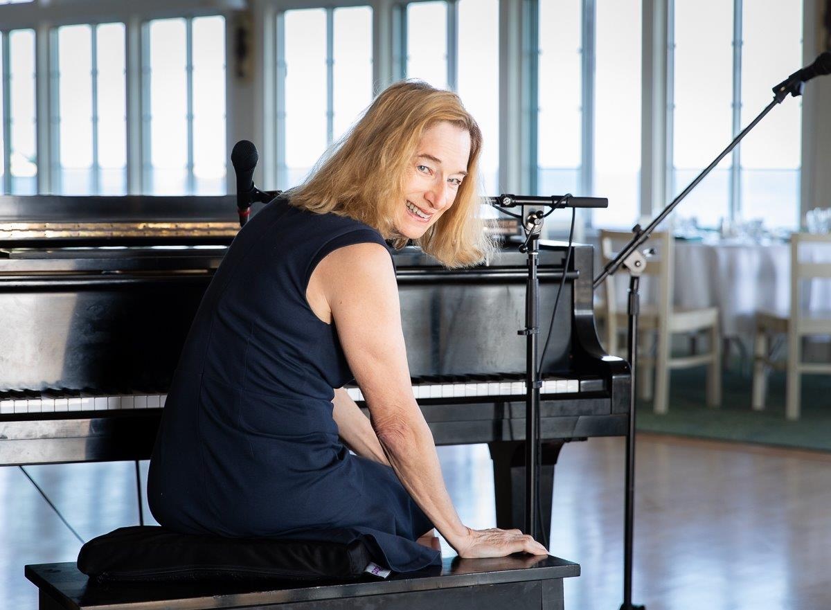 Debbie Sullivan smiling beside a piano